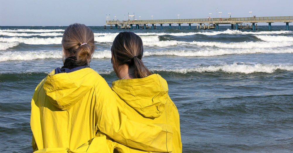 Zwei Frauen mit Regenjacken am Strand