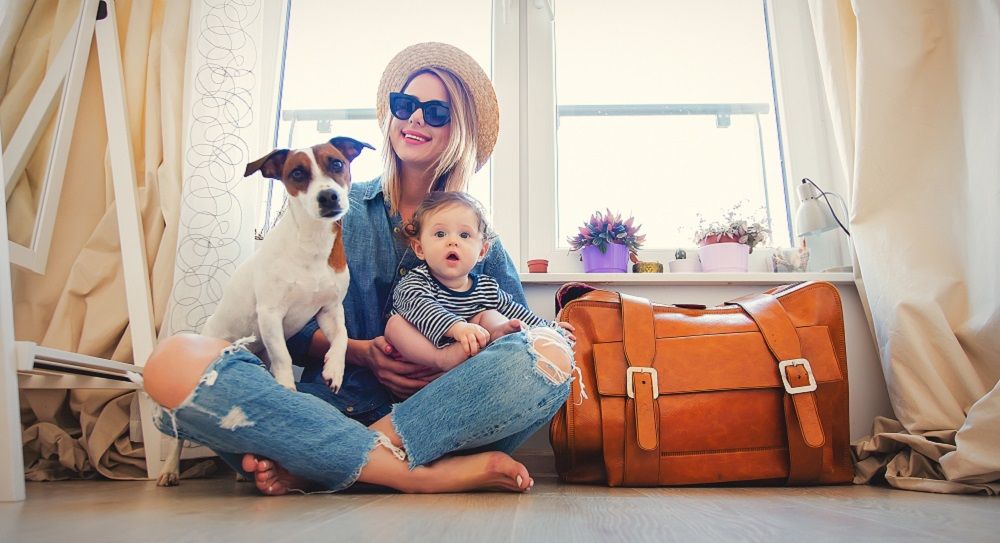 Junge Frau mit Baby und Hund bereitet sich auf die Reise vor