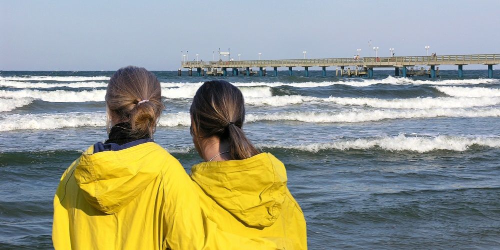 Zwei Frauen mit Regenmänteln an der Ostsee
