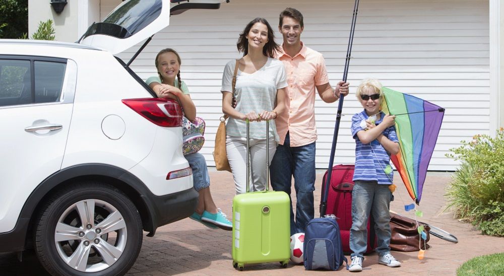 Familie mit Gepäck am Auto